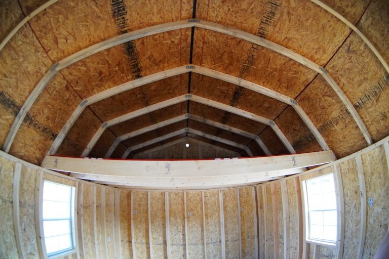 Interior view of an unfinished Premier lofted barn cabin with exposed studs, windows, and a the rear loft.