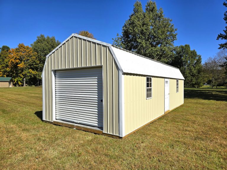 A spacious Premier Lofted Garage featuring Sandstone Metal siding, a bright White Metal Roof, a large roll-up garage door, a side entry door, and windows, set on a green lawn under a clear sky.