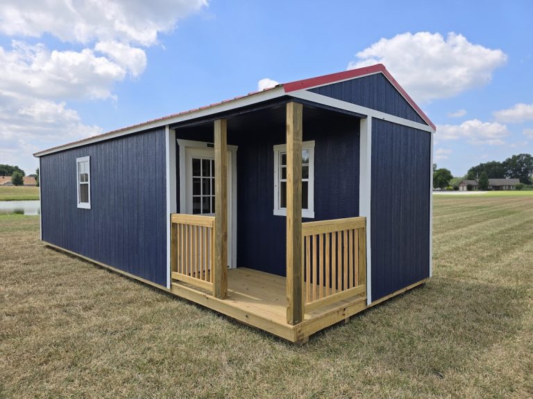 A Navy blue Premier Side Cabin with a Rustic Red roof and a small wooden porch, set in a grassy field under a partly cloudy sky.
